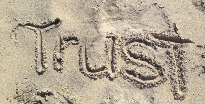 das Wort Trust in Sand geschrieben